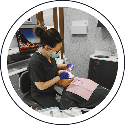 Dental hygienist cleaning a patient's teeth in the treatment chair