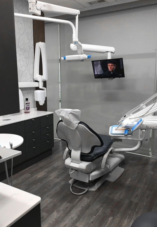 Comfortable dental treatment room with a chair and TV at Deerfoot Dental Centre